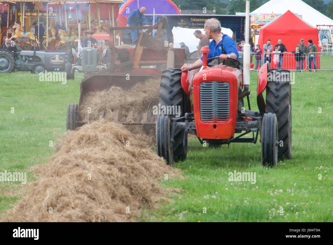 Uomo alla guida e dimostrando rosso trattore vintage a Masham fiera del vapore, Masham, North Yorkshire, Regno Unito Foto Stock