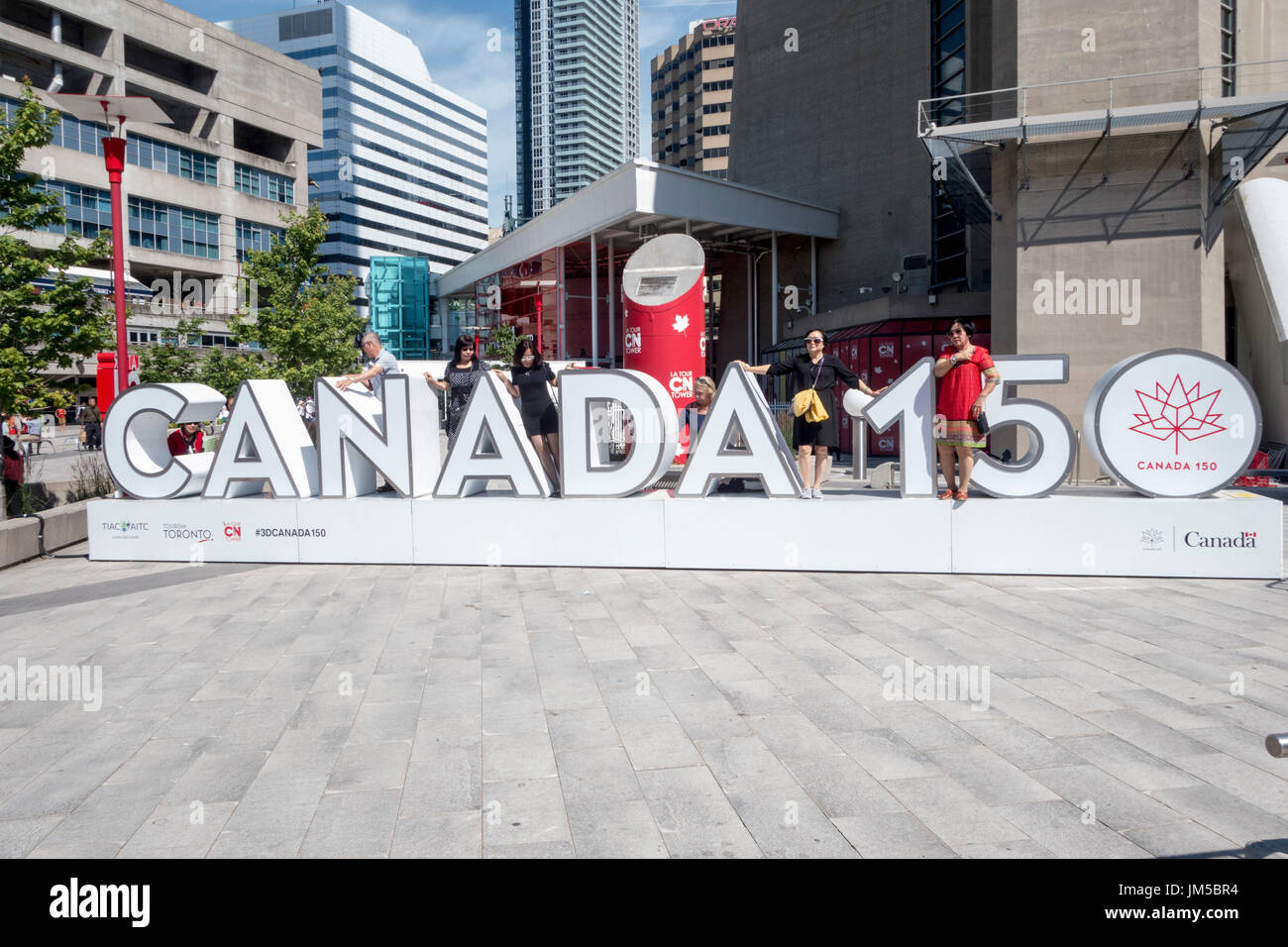 I turisti che pongono al Canada 150 segno esterno della CN tower a Toronto, Ontario, Canada Foto Stock