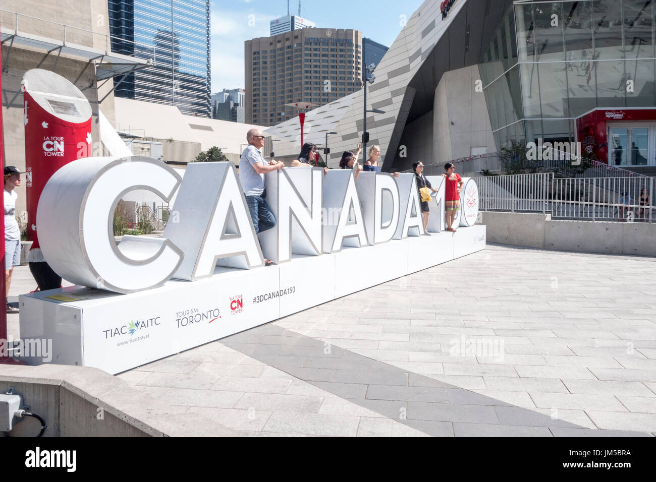 I turisti che pongono al Canada 150 segno esterno della CN tower a Toronto, Ontario, Canada Foto Stock