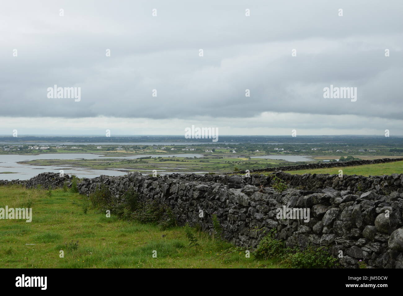 I muri in pietra contro Galway Bay nella contea di Clare, Irlanda occidentale Foto Stock