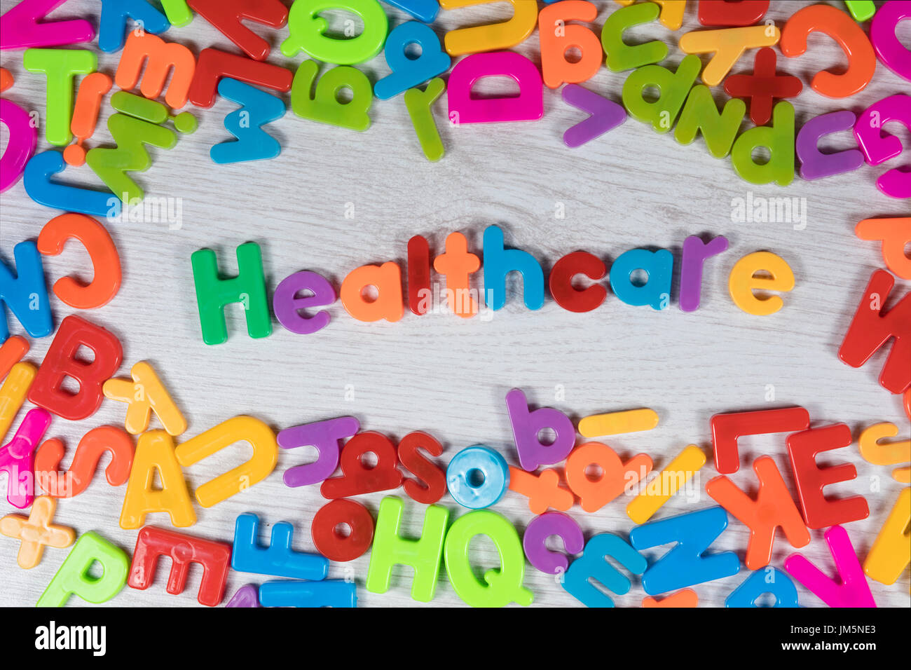 Vivace colorato concetto di assistenza sanitaria di arcobaleno alfabeto colorato lettere che compongono il testo e il telaio circostante su un bianco goffrato Sfondo legno Foto Stock