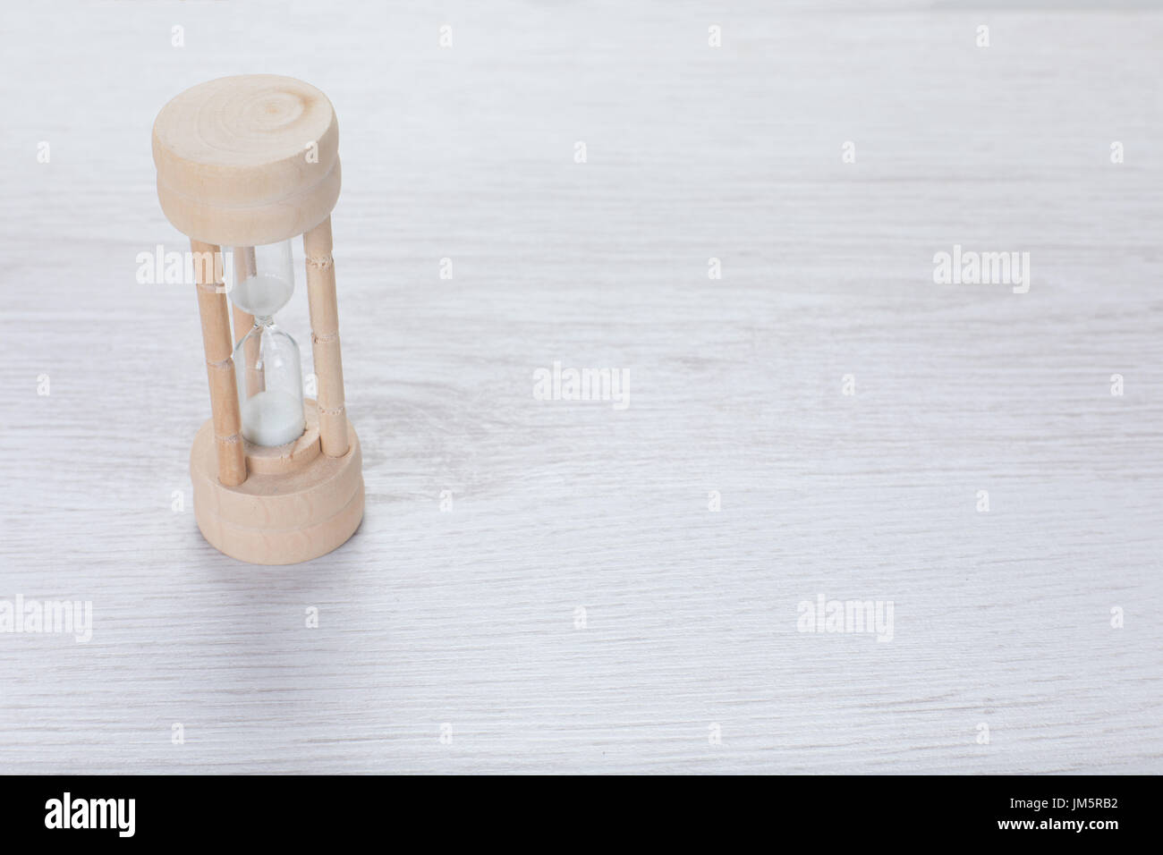 Semplice di legno clessidra misurando il tempo che passa un conteggio alla rovescia fino a un termine in business o come un timer in cottura su bianco goffrato legno con spazio di copia Foto Stock