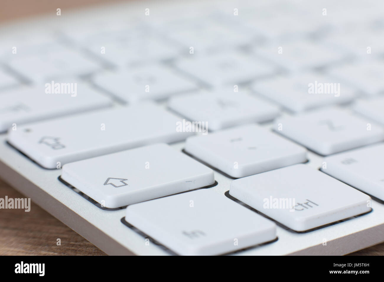Close-up vista isometrica parzialmente sfocate tastiera bianca con molte chiavi di colore bianco sulla parte superiore del tavolo in legno Foto Stock