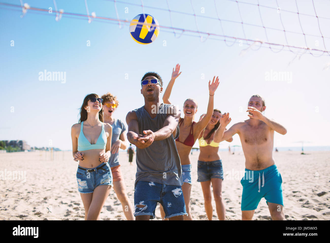 Gruppo di amici a giocare a beach volley in spiaggia Foto Stock