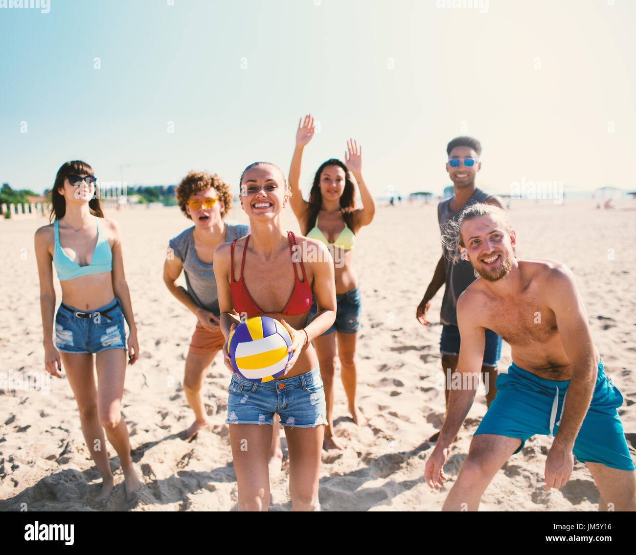 Gruppo di amici a giocare a beach volley in spiaggia Foto Stock