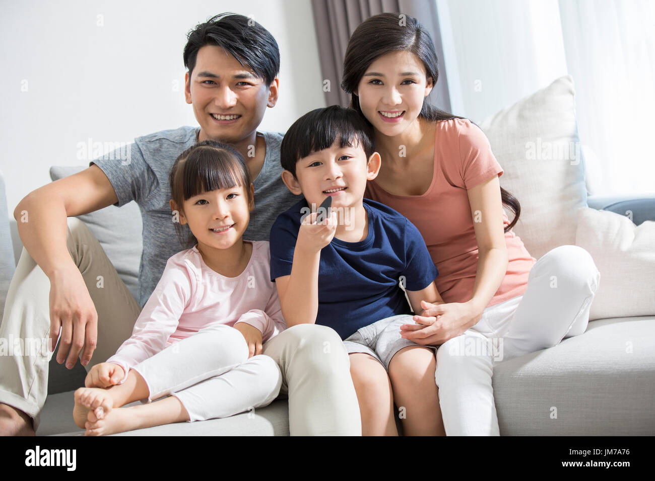 Felice giovane famiglia cinese di guardare la TV Foto Stock