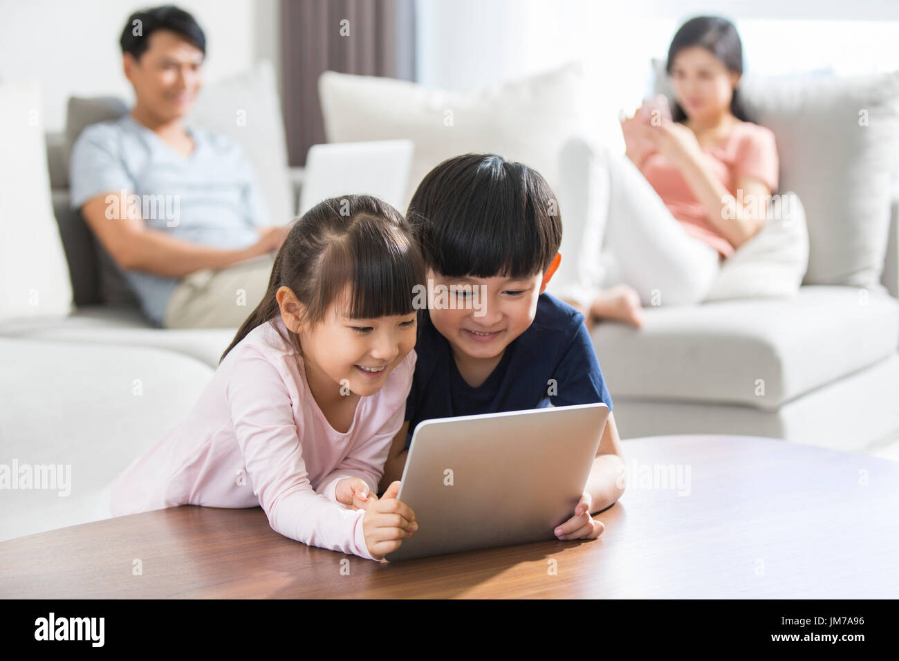Felice giovane famiglia cinese utilizzando i gadget digitale in casa Foto Stock