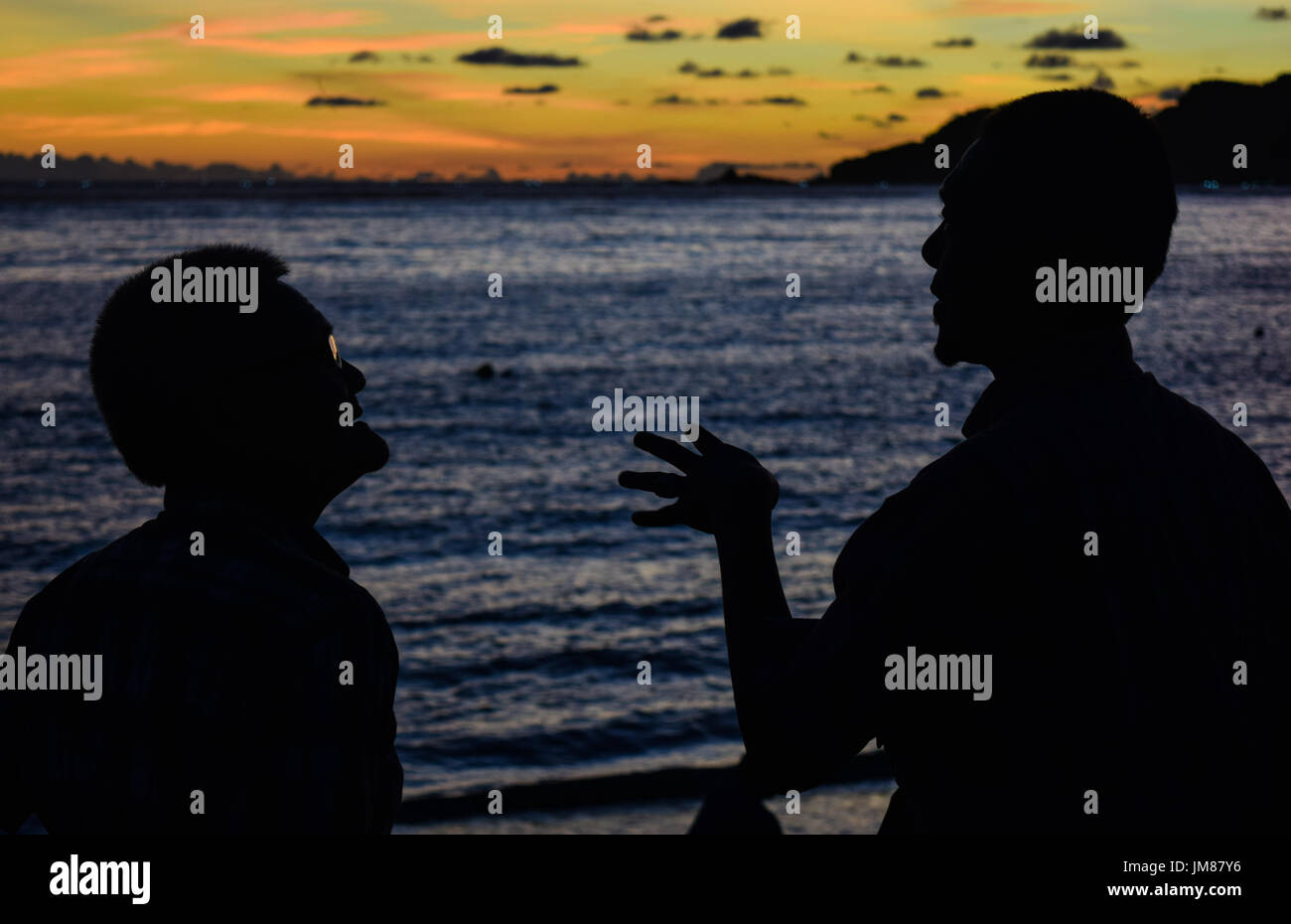 Tramonto a Seger beach, Kuta, Lombok, Indonesia. Ci sono 2 mens avente un po' di conversazione. Foto Stock