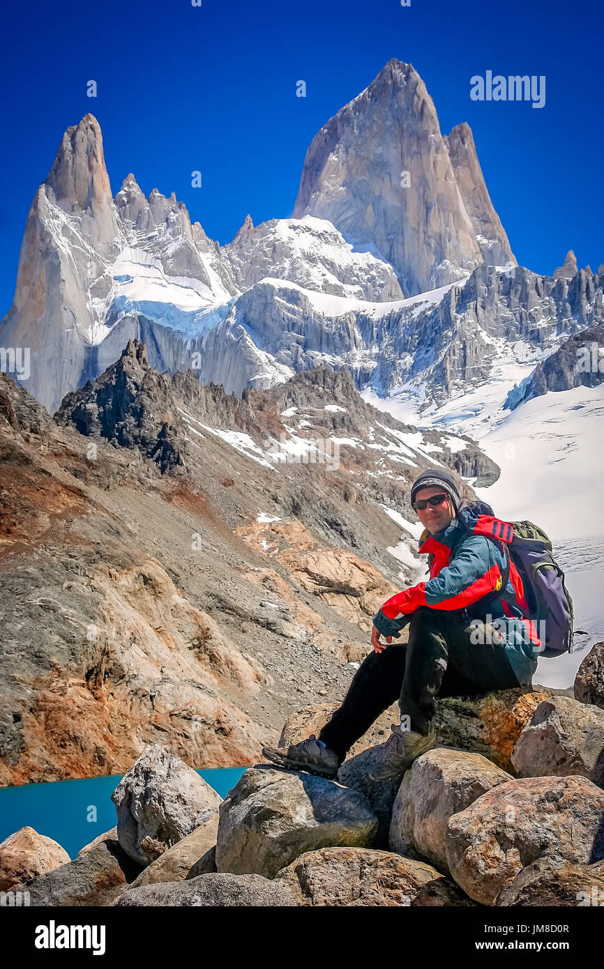 Trekker maschio poggiante sulla roccia di fronte la splendida e imponente Monte Fitz Roy vicino a El Chalten in Patagonia, Argentina Foto Stock