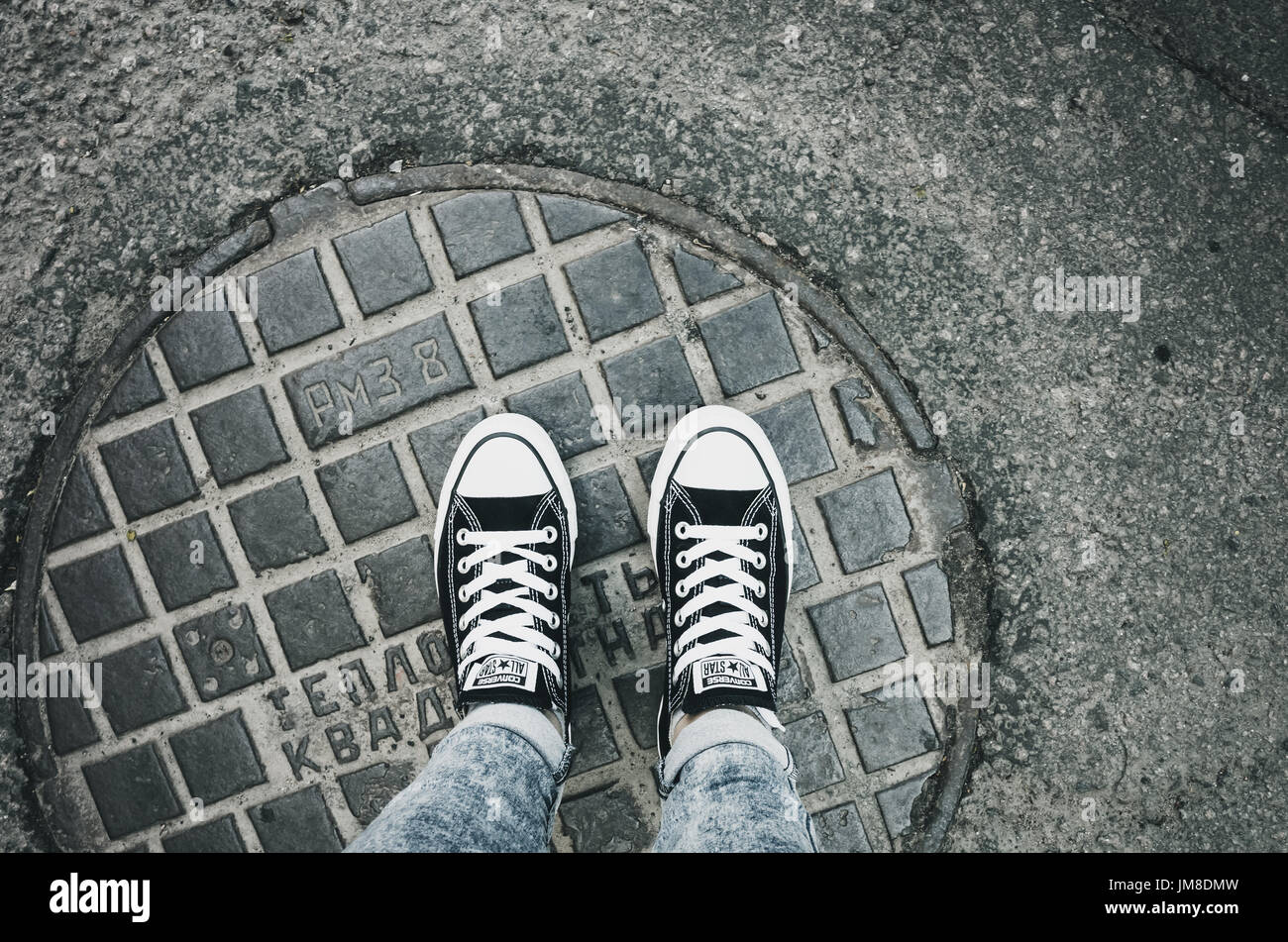 San Pietroburgo, Russia - 30 Maggio 2017: adolescente in piedi in una coppia di tela nera Chuck Taylor All-Stars scarpe casual stand su un urbano chiusino Foto Stock