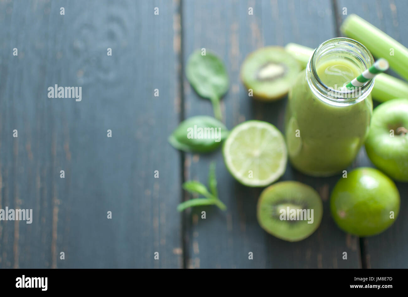 Frullato verde bottiglia con ingredienti sul tavolo di legno Foto Stock