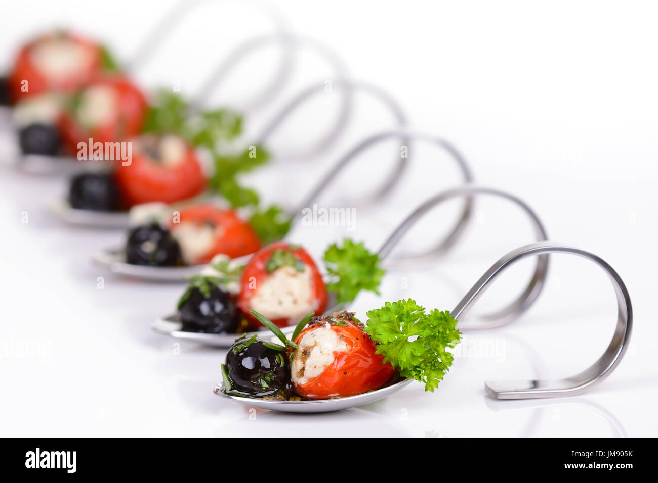 Caldi ripieni Peperoncini ciliegino, olive nere e formaggio feta su antipasto decorativo cucchiai Foto Stock