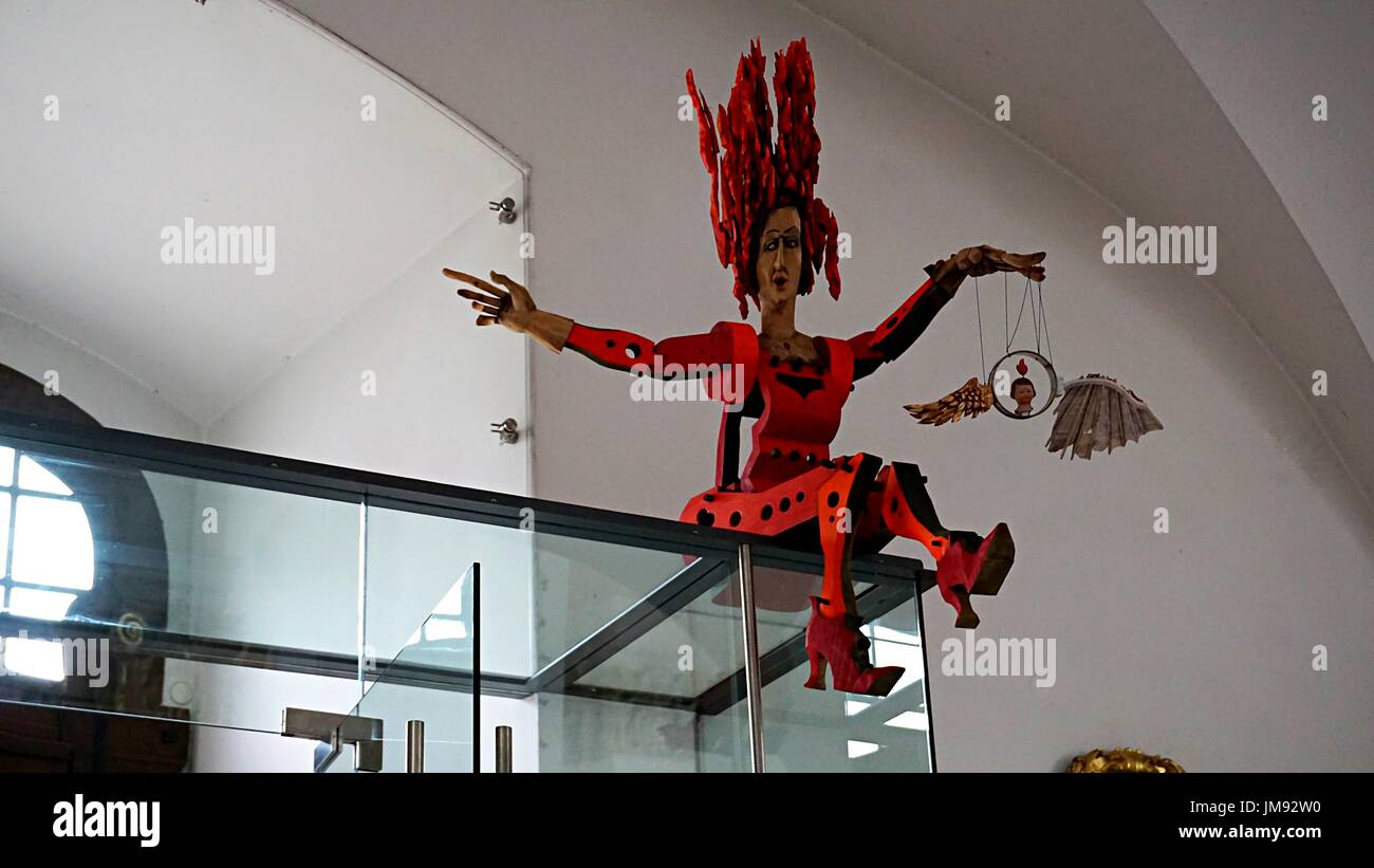 Una donna in rosso arte artigianato seduta oltre all'interno della porta di ingresso della chiesa dei gesuiti nella città vecchia di Heidelberg, Germania. Foto Stock