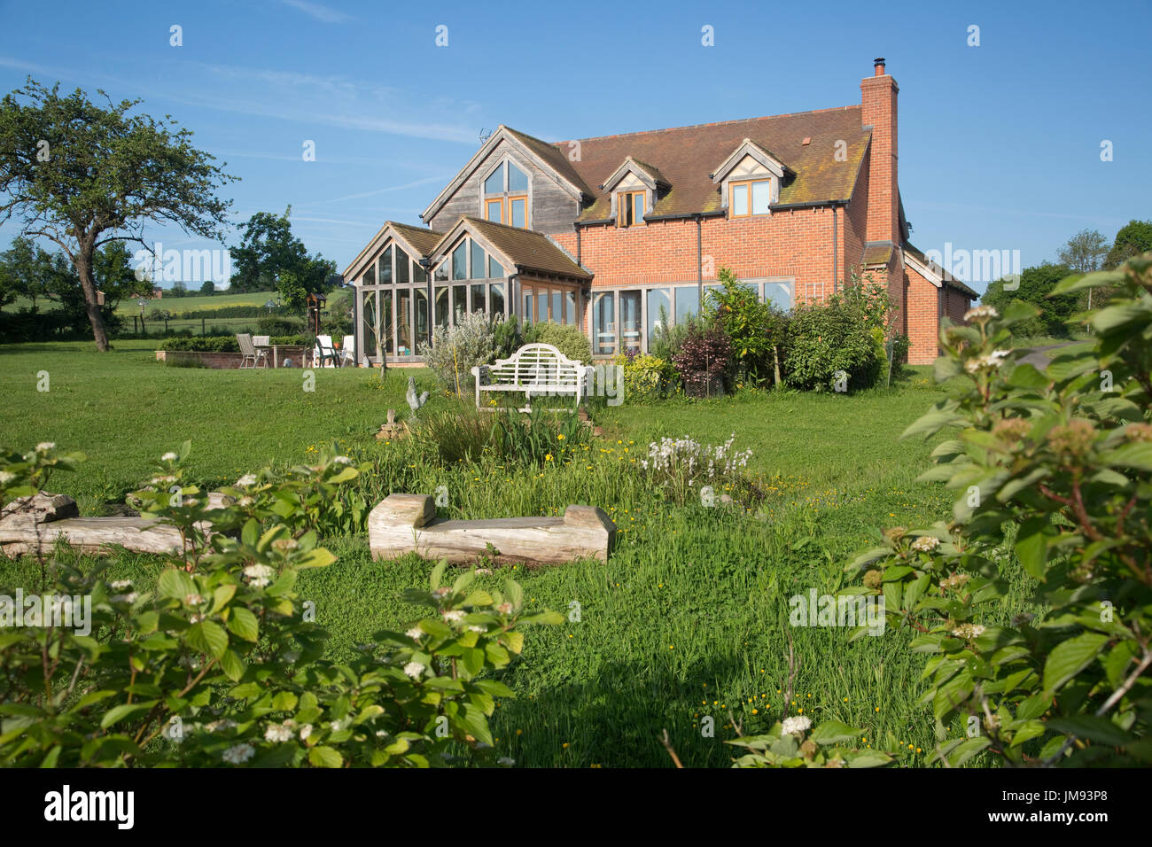 Sedi di registri e wild pond in primo piano di zero energy Cotswold ecohouse costruito di hemcrete REGNO UNITO Foto Stock