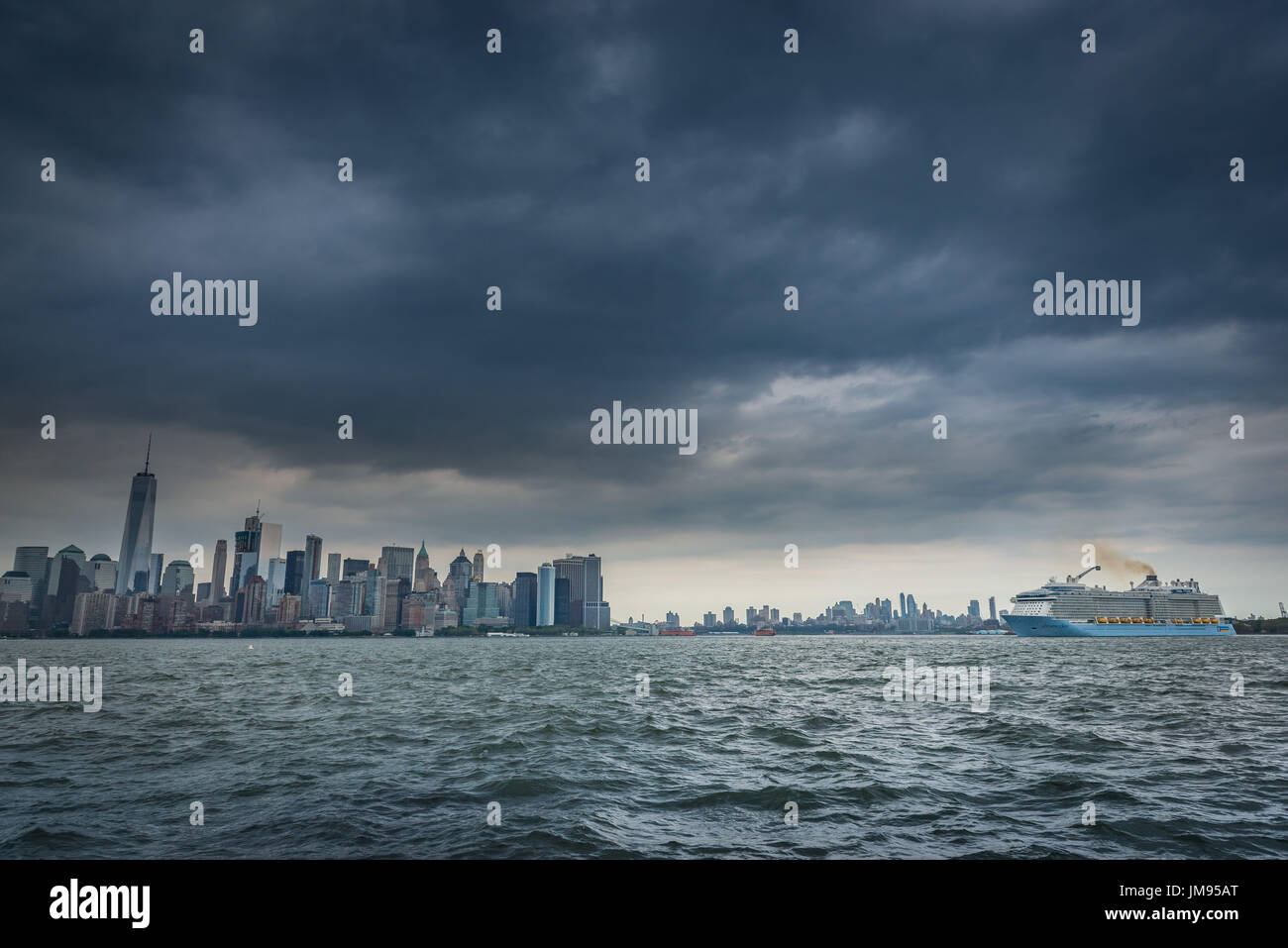Fragoroso scure nuvole temporalesche sindone oltre la parte inferiore dello skyline di Manhattan e un passeggero con una nave da crociera sul fiume Hudson in New York New York, Stati Uniti d'America Foto Stock