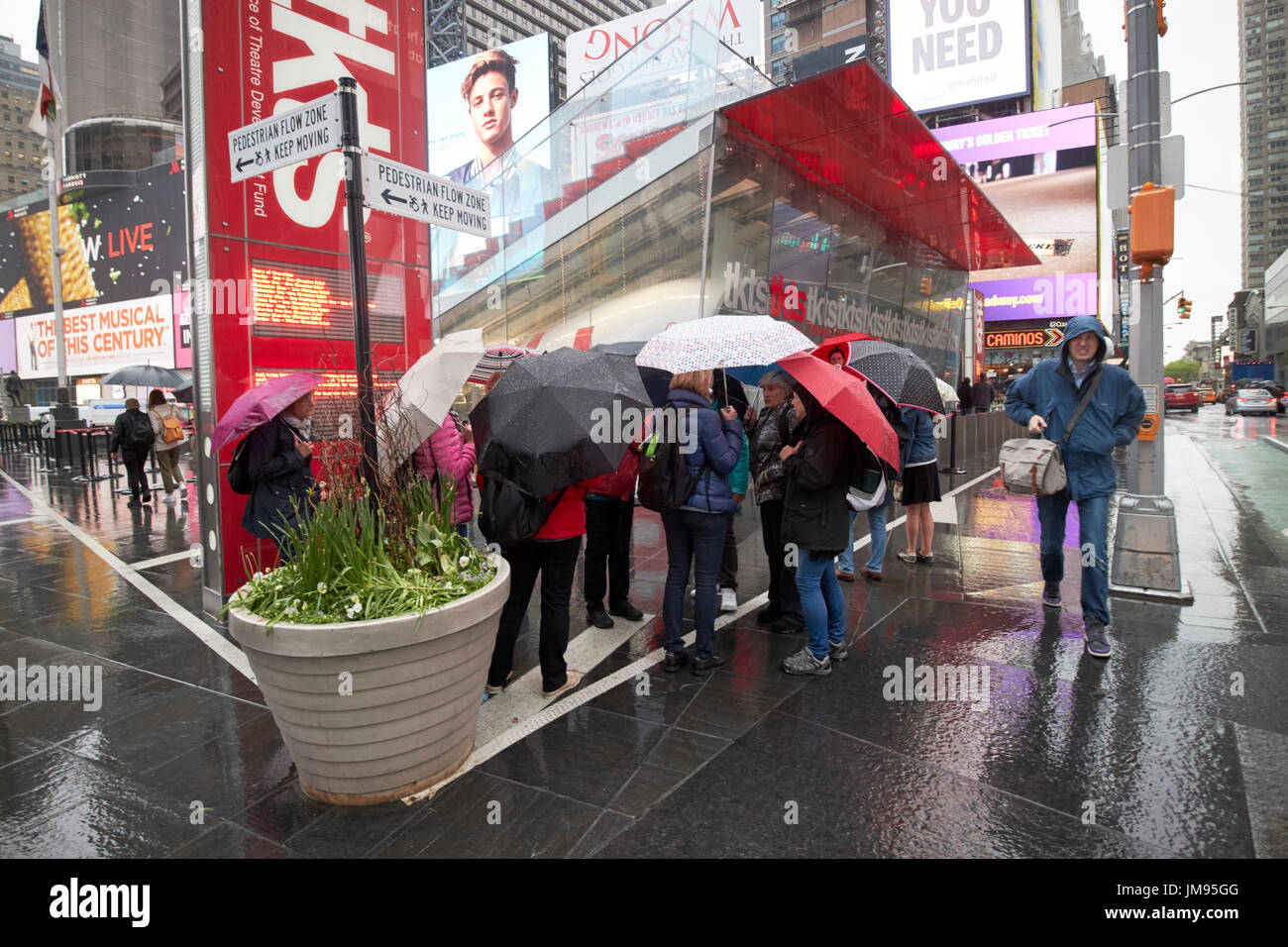 Persone che trasportano gli ombrelli in attesa in stallo tkts sotto la pioggia di New York City STATI UNITI D'AMERICA Foto Stock