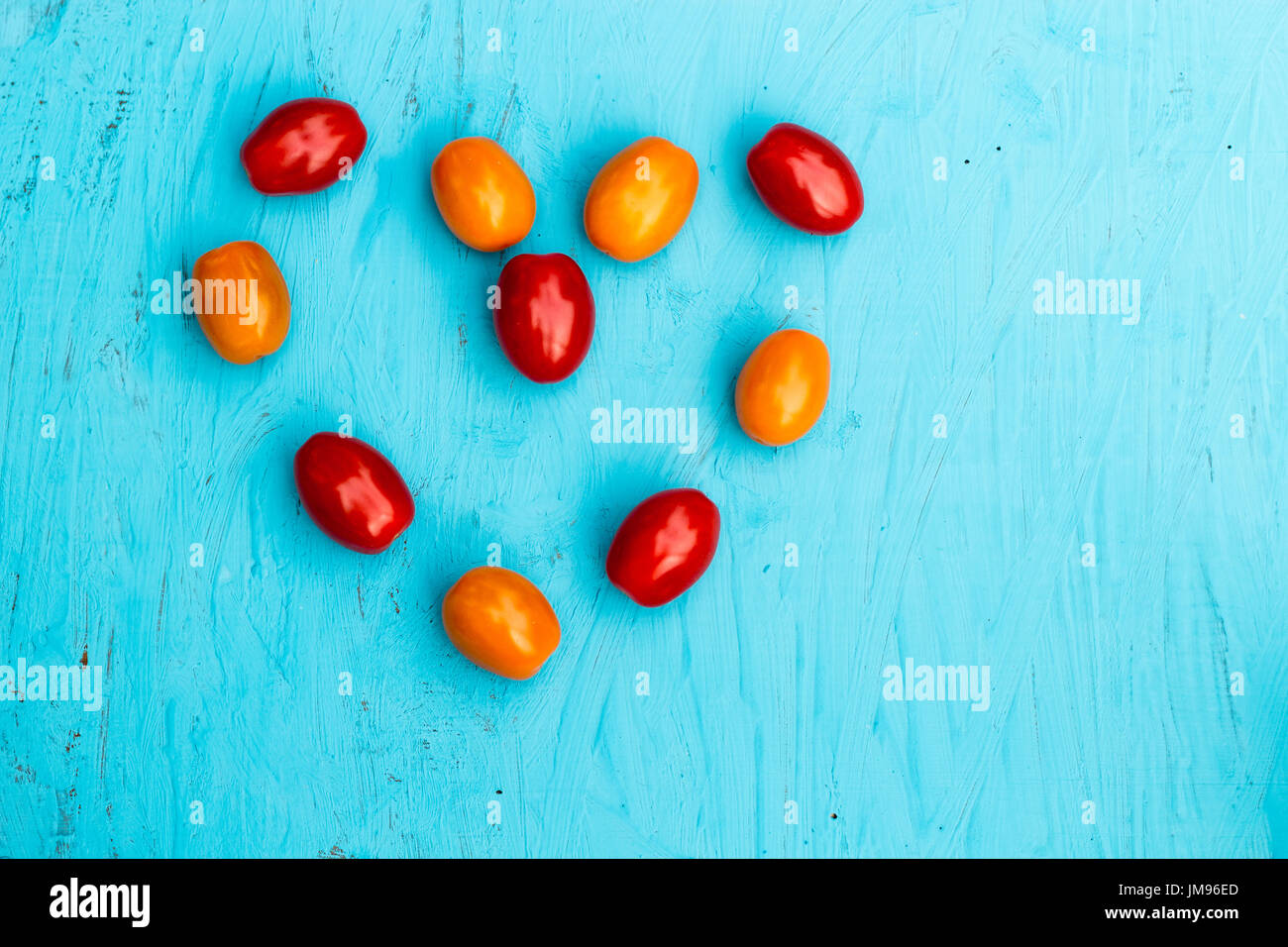 Cuore del piccolo, colorato pomodori ciliegia su uno sfondo blu Foto Stock