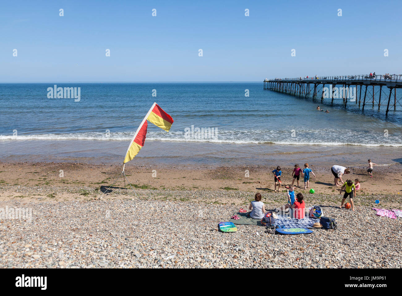 Un giallo e rosso di sicurezza bandiera di avvertimento sulla spiaggia di Saltburn dal mare,Inghilterra,UK Foto Stock