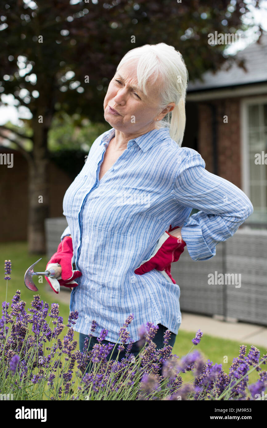 Senior donna che soffre di mal di schiena mentre il giardinaggio a casa Foto Stock