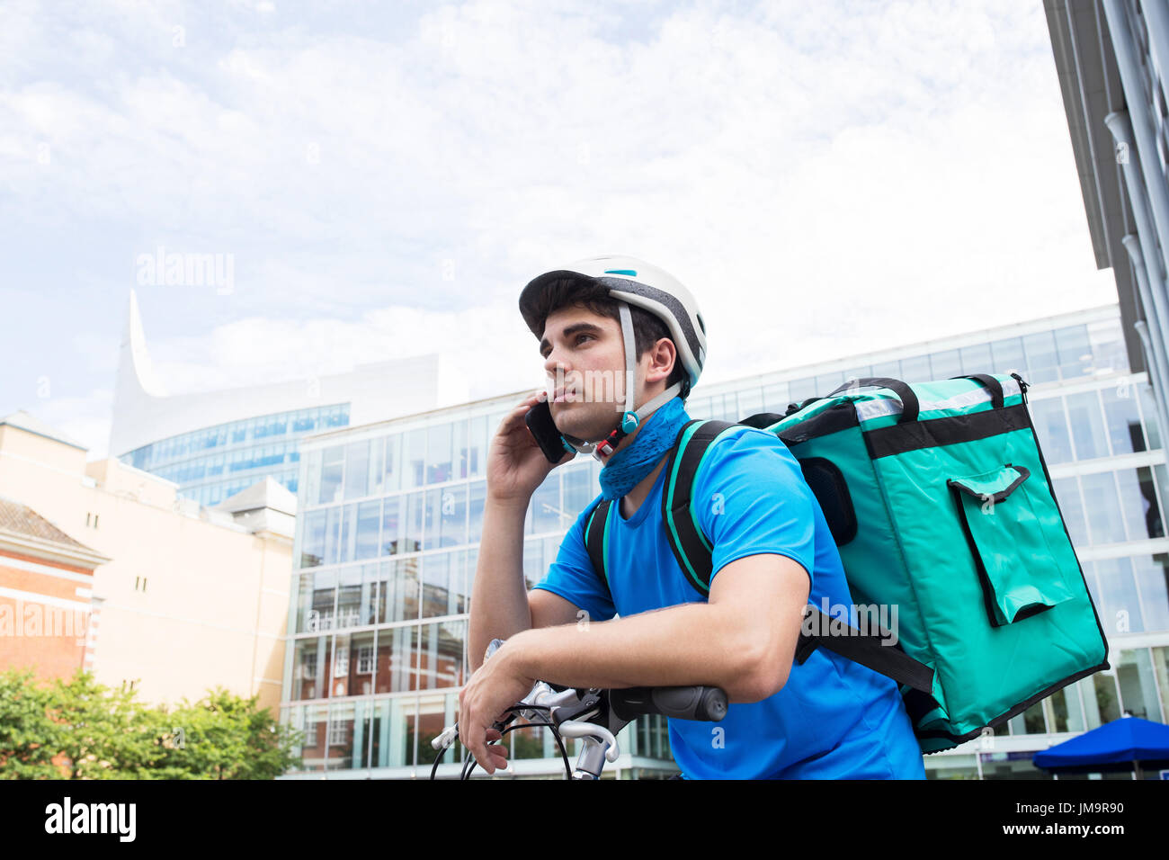 Servizi di corriere in bicicletta a consegnare il cibo in città utilizzando il telefono cellulare Foto Stock
