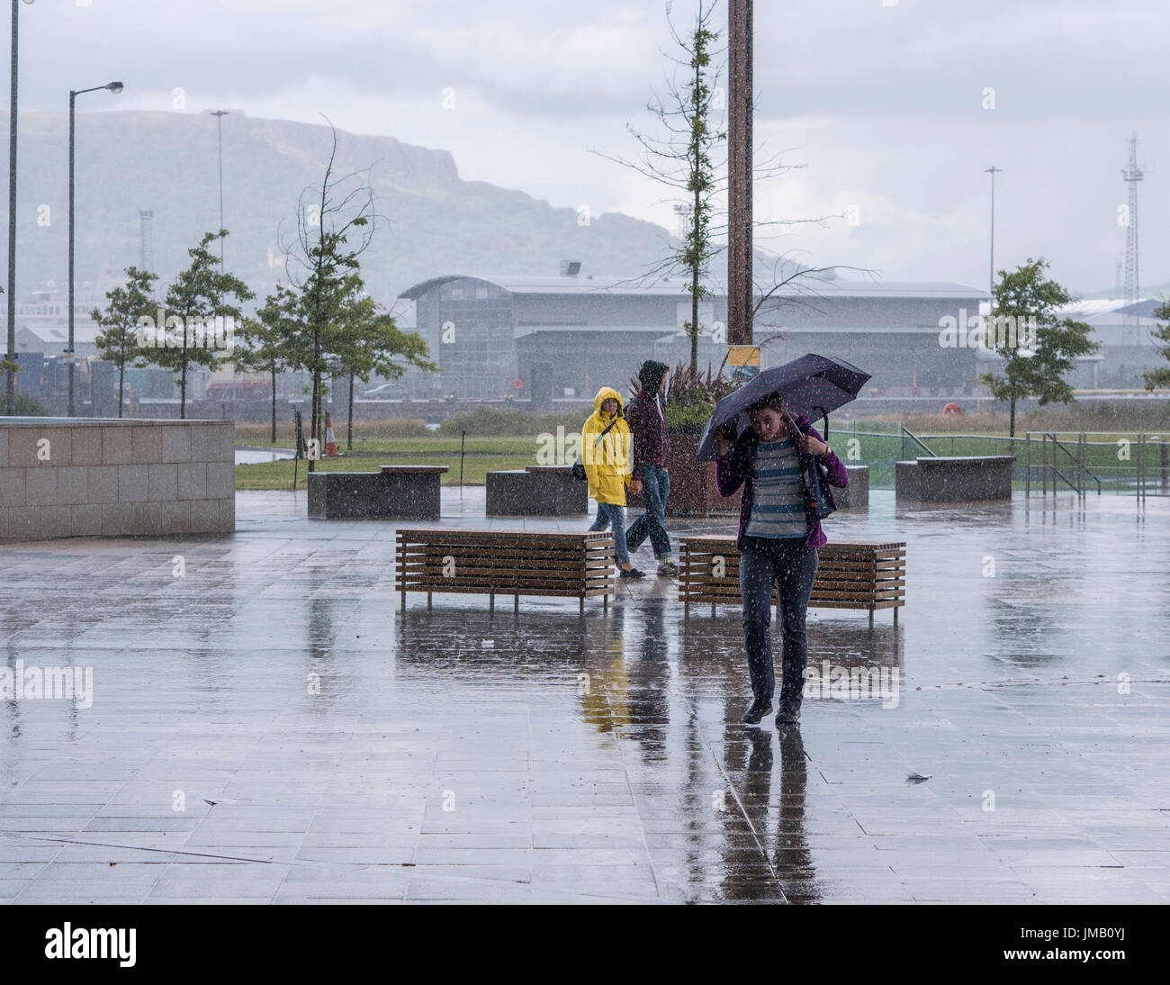 Belfast, Irlanda del Nord, Regno Unito. Il 27 luglio 2017. Regno Unito meteo: una giovane donna ripari sotto un ombrello in un giorno di Pesanti rovesci tra alcuni periodi luminosi a Belfast. Il credito J Orr/Alamy Live News Foto Stock