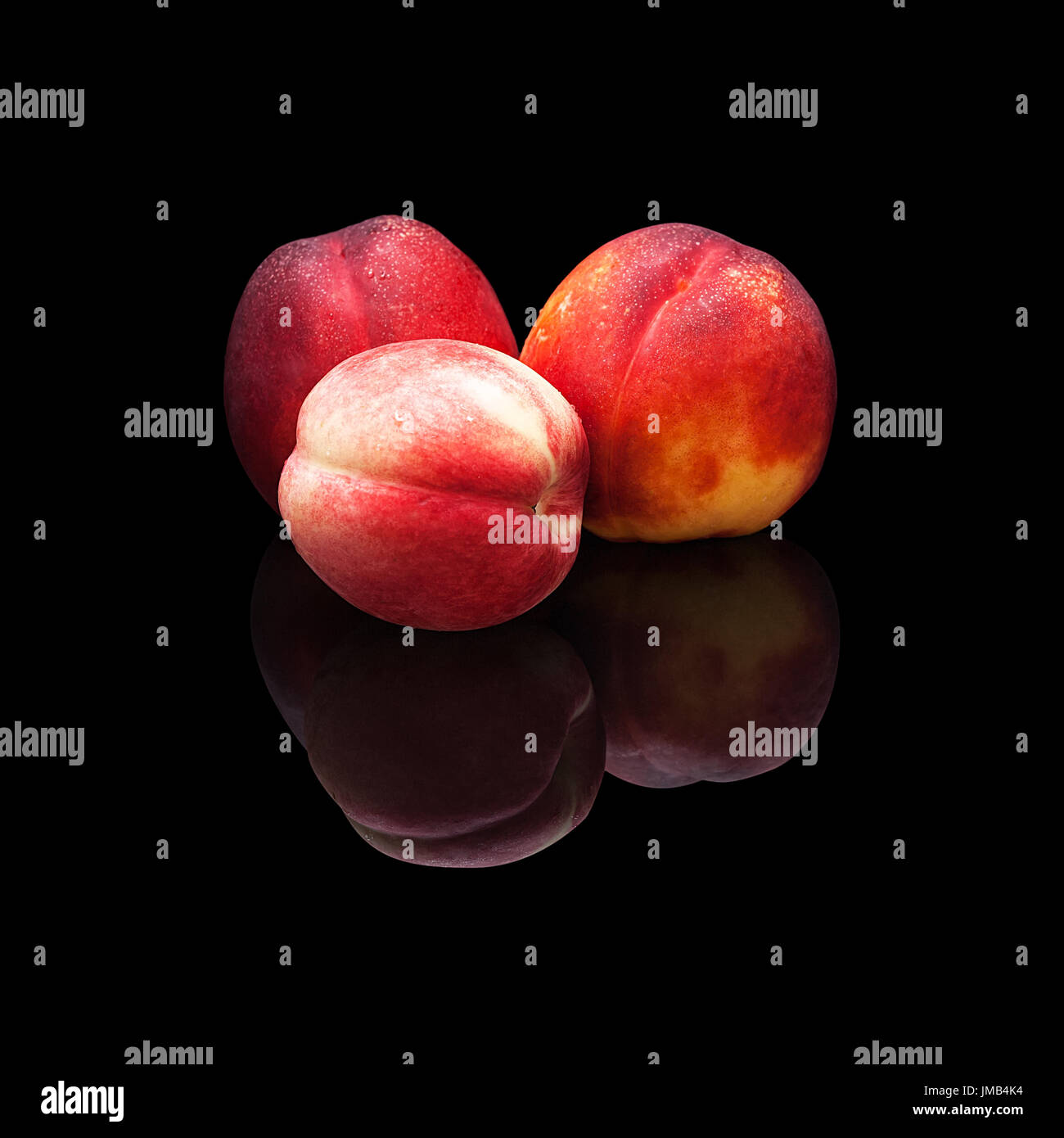 Tre mature le pesche noci su uno sfondo nero isolato con una vera riflessione Foto Stock
