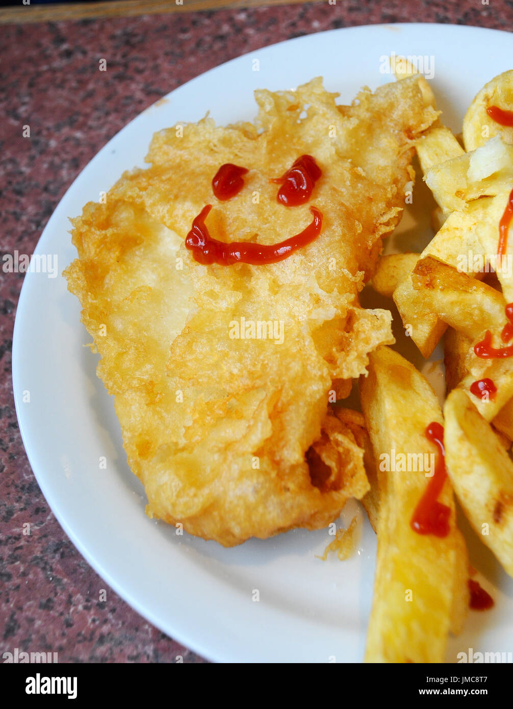 Per i pasti dei bambini di pesce e patatine fritte con una faccina sorridente disegnato in salsa di pomodoro Foto Stock