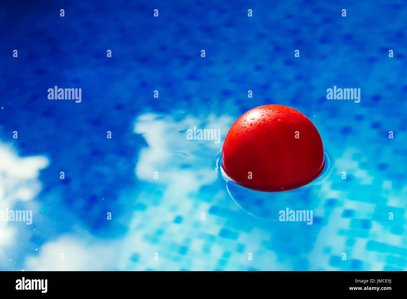 Sfera rossa galleggianti in azzurro piscina acqua, puzzle in piscina per attività estive e ricreazione Foto Stock