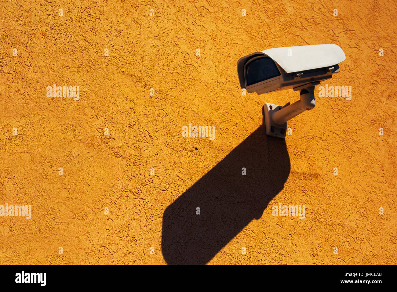 Una telecamera di sicurezza sulla parete gialla, la moderna tecnologia di sorveglianza sulla facciata di edificio con ombra Foto Stock