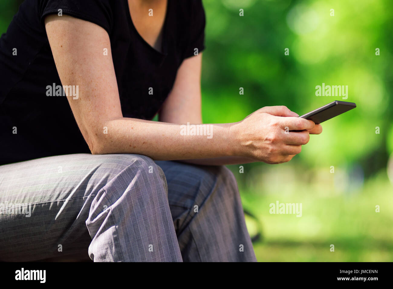 Social network addict utilizza lo smartphone all'aperto nel parco per condividere, seguire e post ai social media Foto Stock