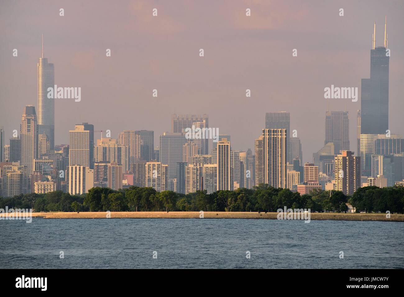 Chicago, Illinois, Stati Uniti d'America. Un muto sunrise illuninates Chicago skyline attraverso un estate haze oltre il Lago Michigan. Foto Stock