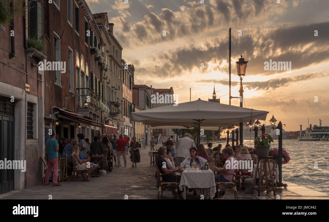 Pasti al fresco come il sole che va giù in un ristorante del lungomare sull isola della Giudecca, Venezia, Italia. Foto Stock