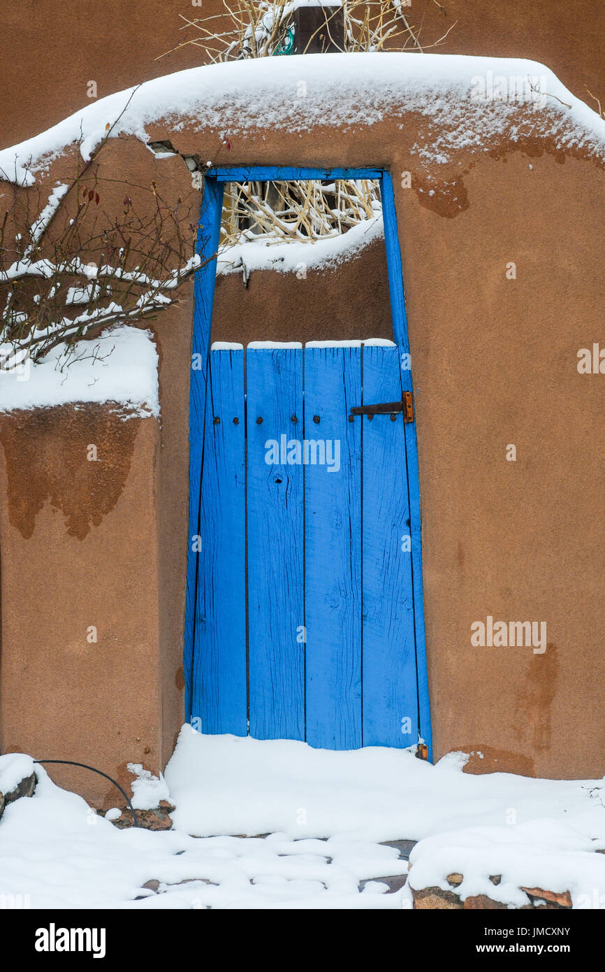 Adobe porta con la porta blu e neve in Albuquerque, Nuovo Messico, Stati Uniti d'America. Foto Stock