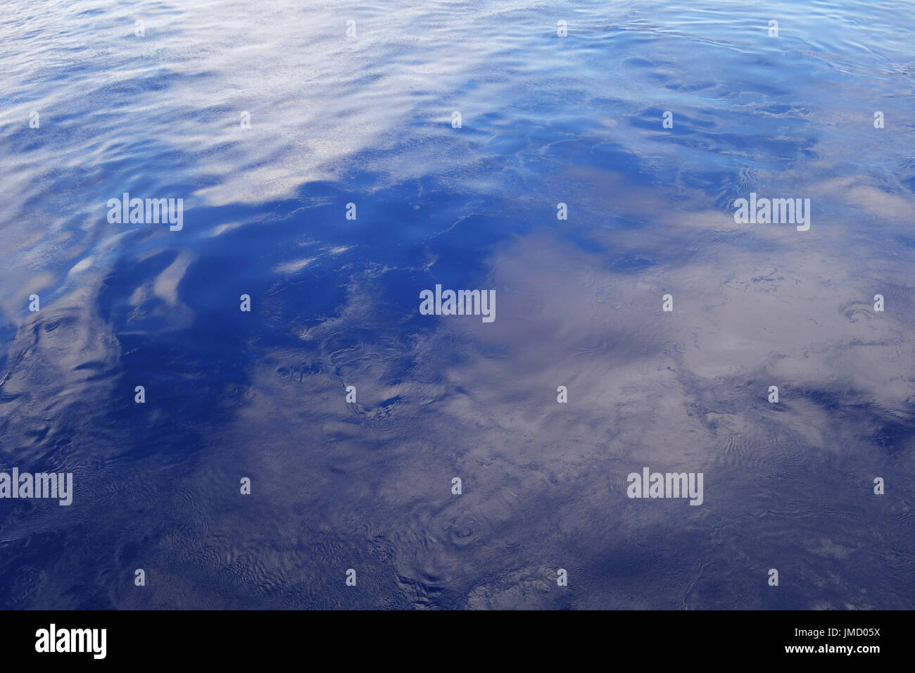 Oceano liscia superficie che riflette le nuvole e il cielo con le ondulazioni Foto Stock