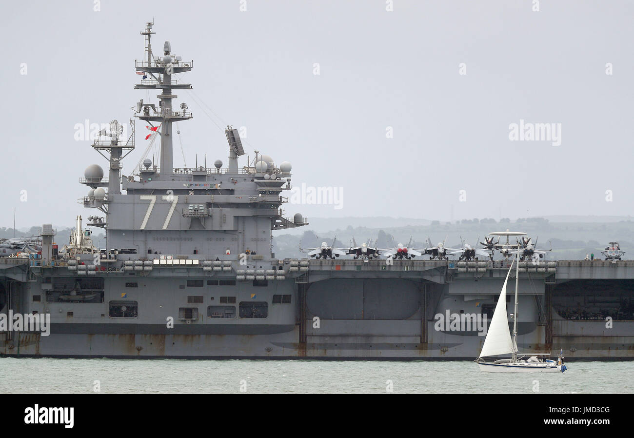 Una barca a vela passa la US Navy Nimitz-class portaerei USS George H.W. Bush come si stabilisce al di ancoraggio fuori coastbefore partecipa n esercizio guerriero sassone 2017 nel Nord dell'Oceano Atlantico. Foto Stock