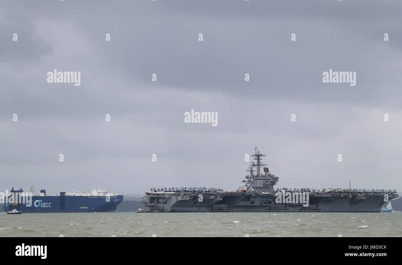 La vettura UECC transporter spedire Auto Eco passa la US Navy Nimitz-class portaerei USS George H.W. Bush come si stabilisce al di ancoraggio fuori coastbefore partecipa n esercizio guerriero sassone 2017 nel Nord dell'Oceano Atlantico. Foto Stock