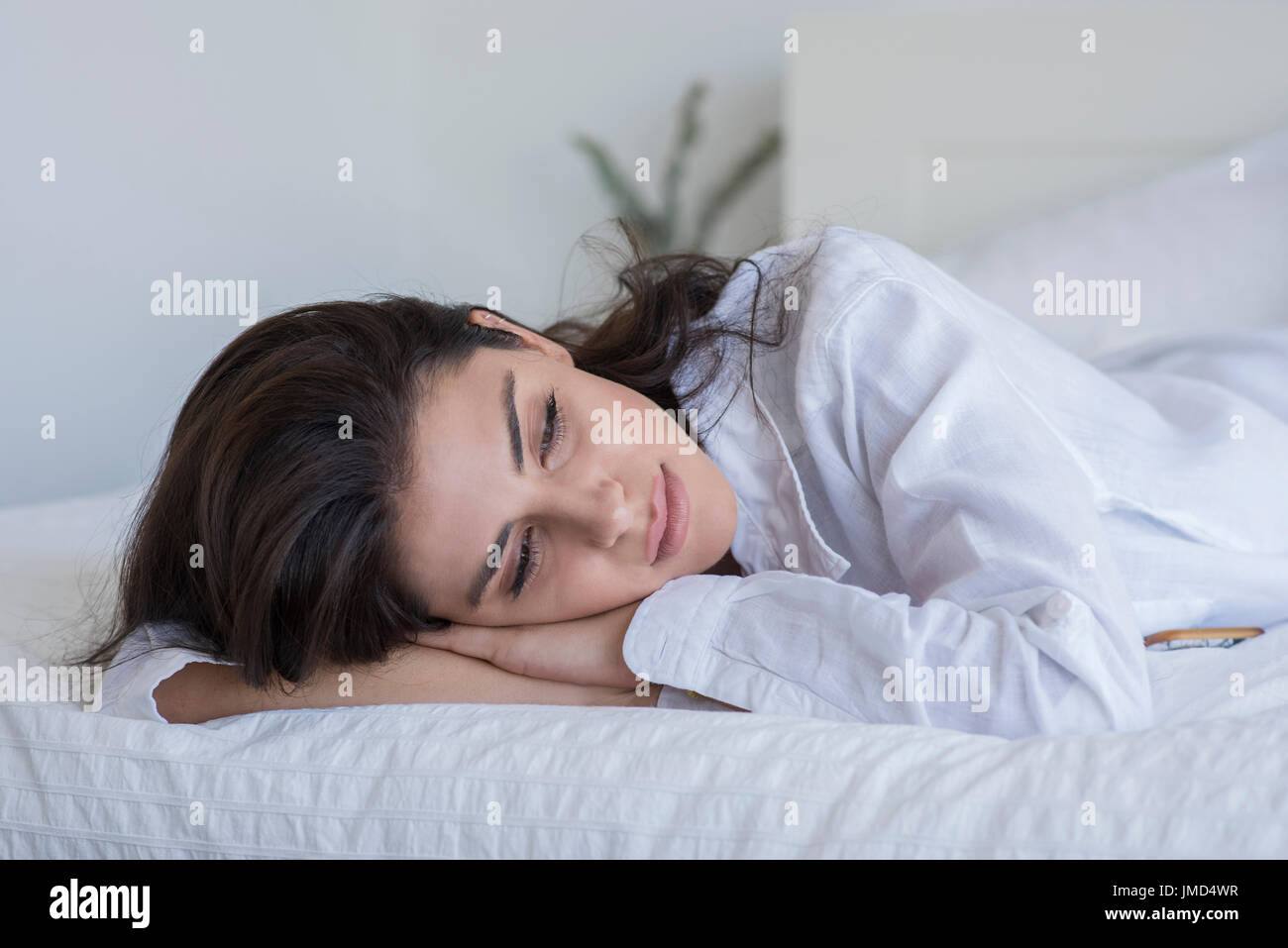 Giovane donna giaceva sul letto di indossare una camicia bianca. Foto Stock