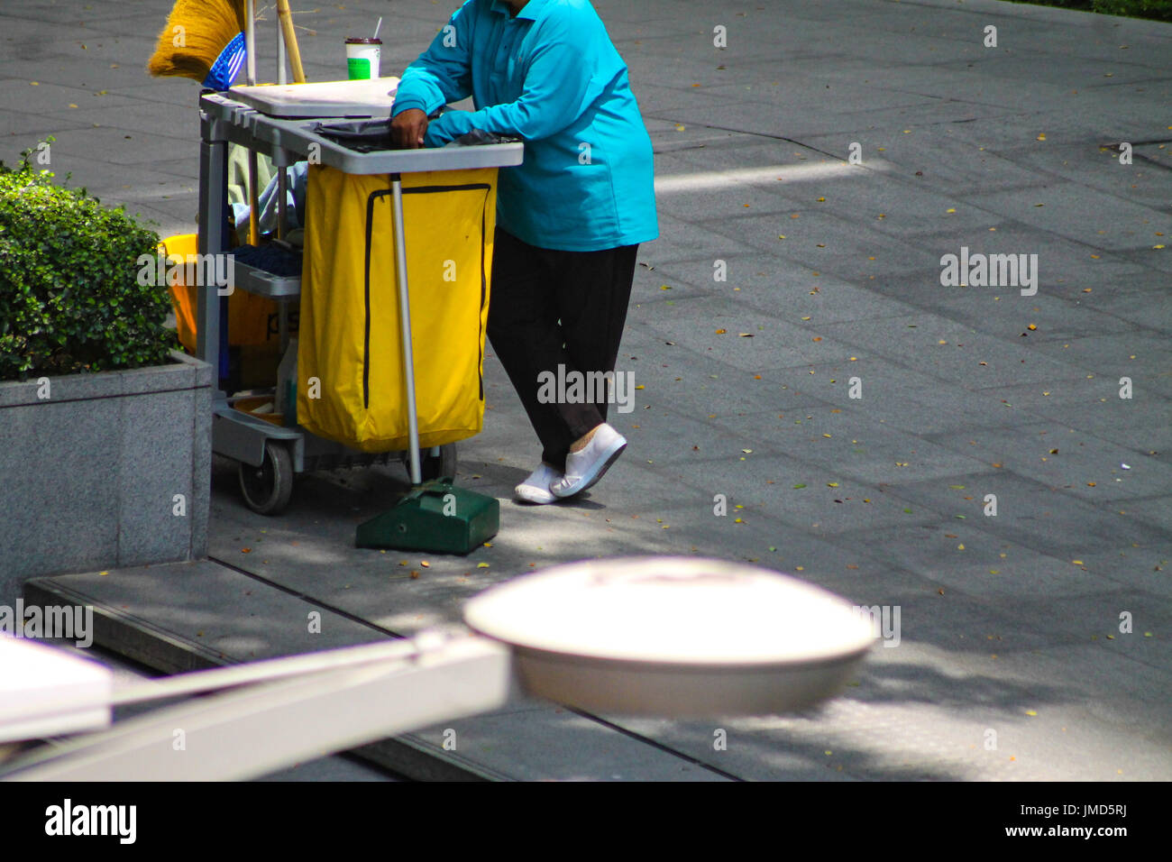 Un pulitore di strada che fa una pausa accanto a un cestino nella città di Bangkok, Thailandia Foto Stock