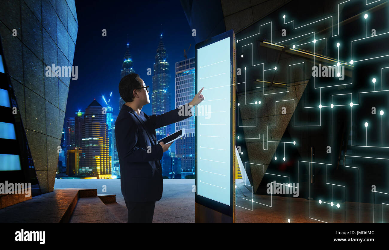 Smart imprenditore toccare lo schermo per ricercare le informazioni di reti di comunicazione intelligenti di cose . Scena notturna con la città moderna di sfondo Foto Stock