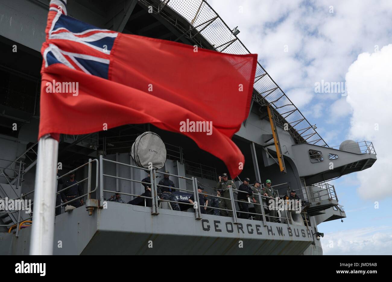 Una red ensign da un traghetto facendo scendere i passeggeri vola a fianco del Navy US Nimitz-class portaerei USS George H.W. Bush come si stabilisce al di ancoraggio al largo prima di esso partecipa in esercizio guerriero sassone 2017 nel Nord dell'Oceano Atlantico. Foto Stock