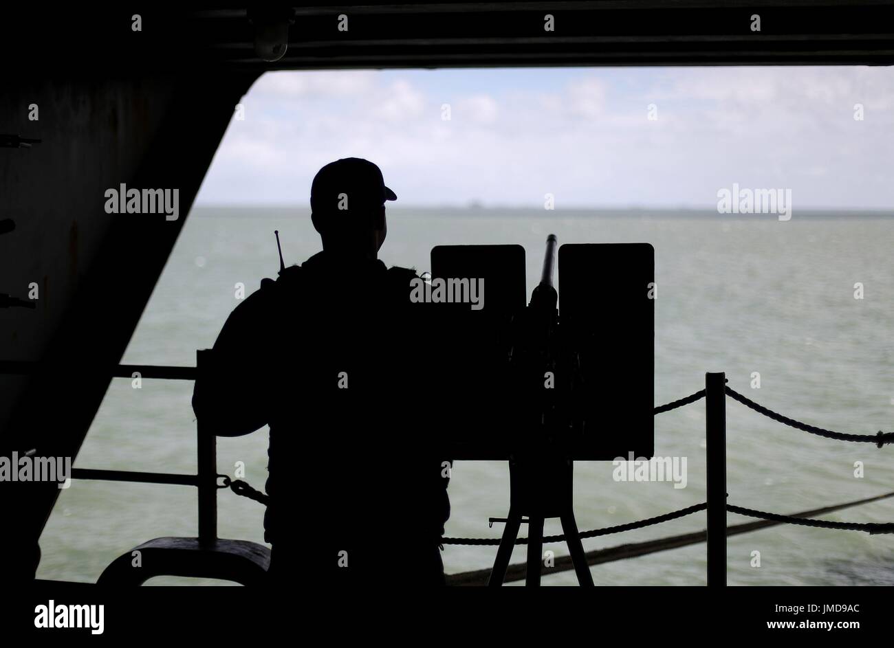Un membro di equipaggio mans una pistola come egli continua a guardare fuori a bordo della US Navy Nimitz-class portaerei USS George H.W. Bush come si stabilisce al di ancoraggio al largo prima di esso partecipa in esercizio guerriero sassone 2017 nel Nord dell'Oceano Atlantico. Foto Stock