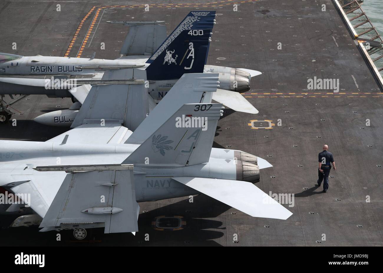 Un membro di equipaggio passeggiate passato 2 F-18 getti a bordo della US Navy Nimitz-class portaerei USS George H.W. Bush come si stabilisce al di ancoraggio al largo prima di esso partecipa in esercizio guerriero sassone 2017 nel Nord dell'Oceano Atlantico. Foto Stock