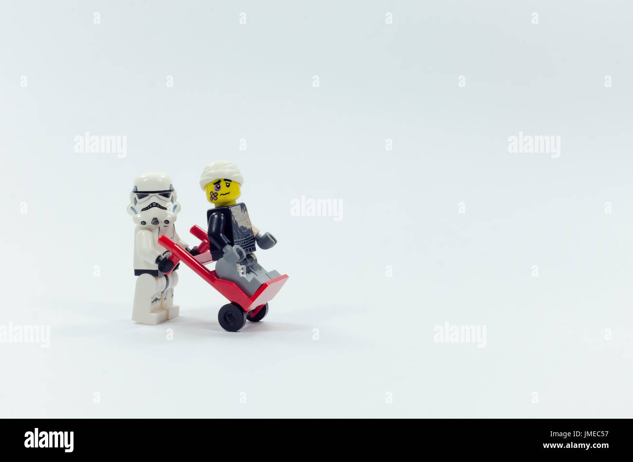 Lego feriti Darth Vader seduti sul carrello mentre storm trooper spingendolo. isolato su sfondo bianco. Foto Stock