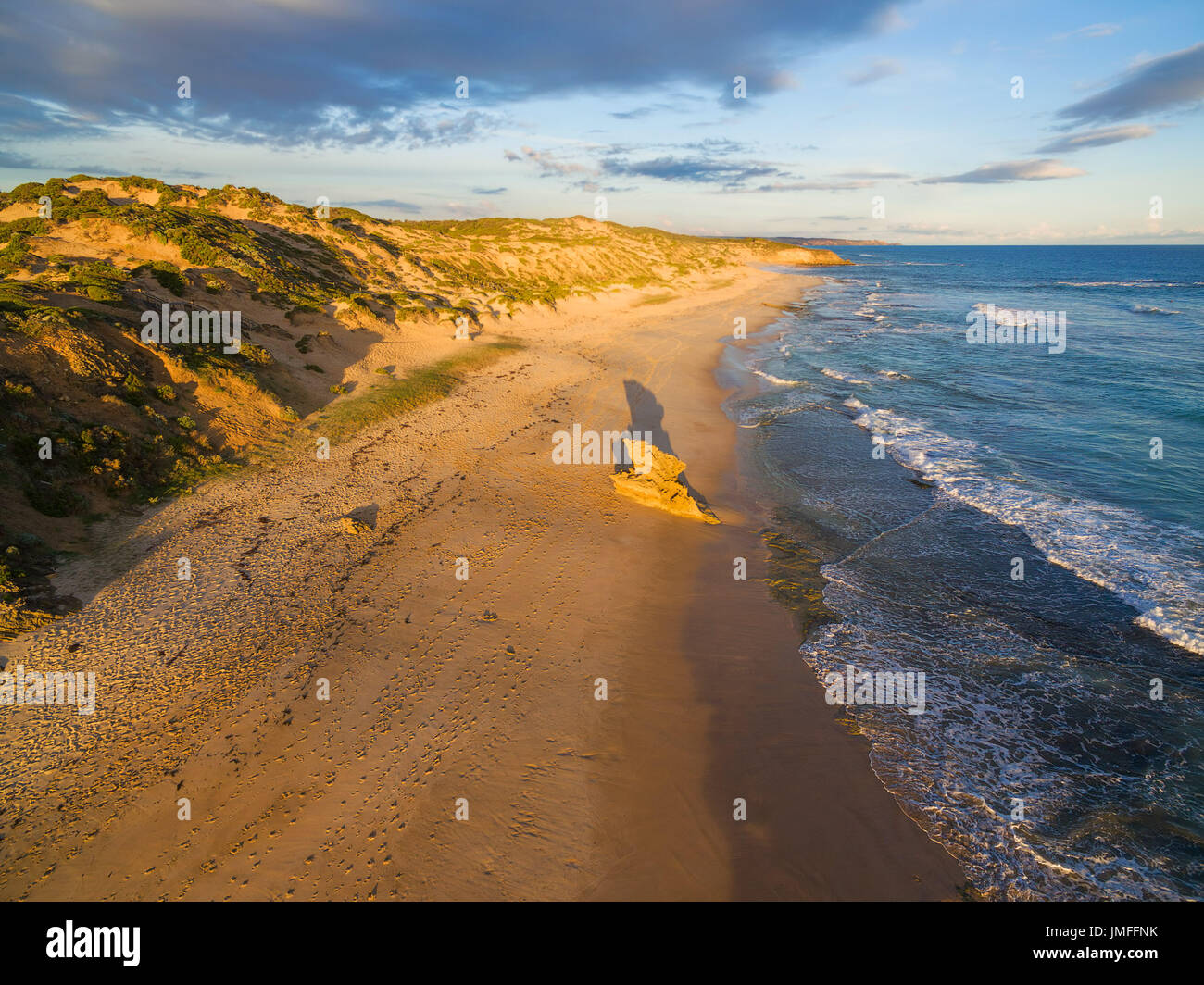 Roccia calcarea e la formazione con una lunga ombra sulla spiaggia dell'oceano incandescente al tramonto Foto Stock
