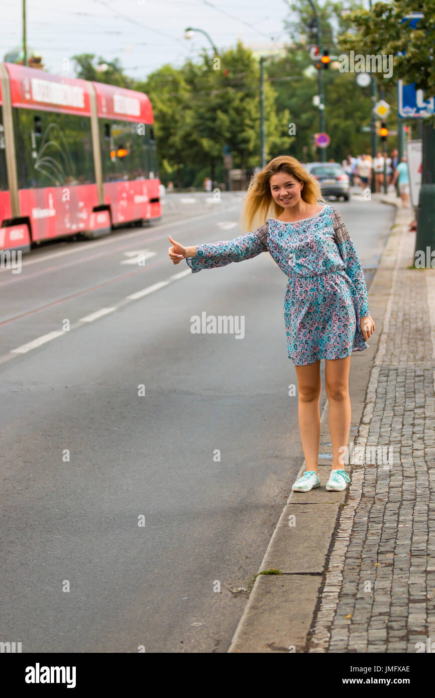 Giovane donna facendo il sollevatore-escursionismo in una strada di una città Foto Stock