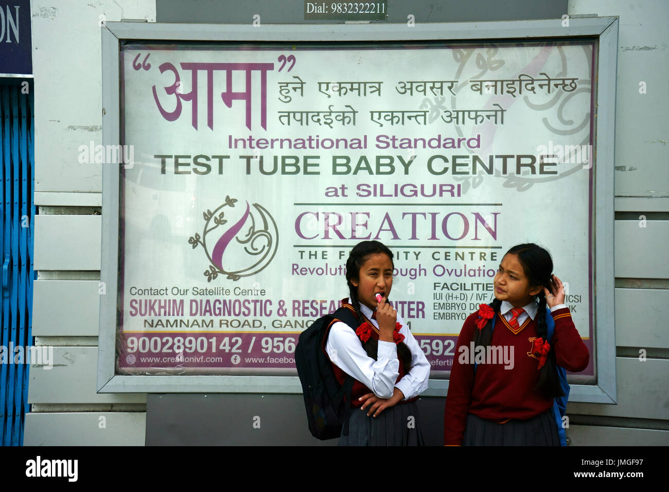 Giovani ragazze adolescenti la cordatura di fronte una pubblicità billborad Provetta Baby, Centro citta Gangtok, Sikkim, India Foto Stock
