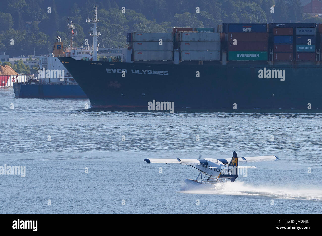 Porto aria turbo otter idrovolanti prendendo il largo verso il gigante evergreen nave container mai "Ulisse" nel porto di Vancouver, British Columbia, Canada Foto Stock