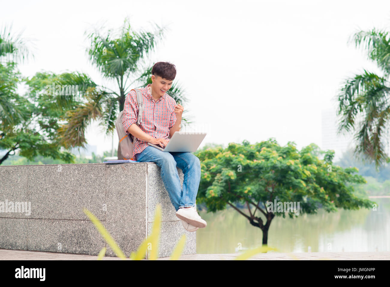 Sorridente studente di college seduti sulla scalinata con laptop all'aperto Foto Stock