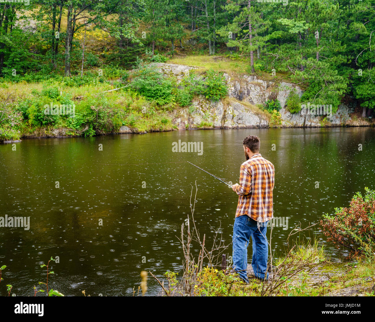 Penisola Superiore, Michigan, Agosto 11, 2016: un pescatore dedicato è la pesca in un fiume vicino a Marquette, Michigan Foto Stock