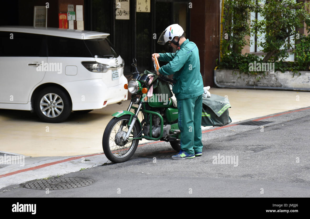 Taiwan post office lavoratore la consegna di posta su un motociclo verde a persone home. Foto Stock